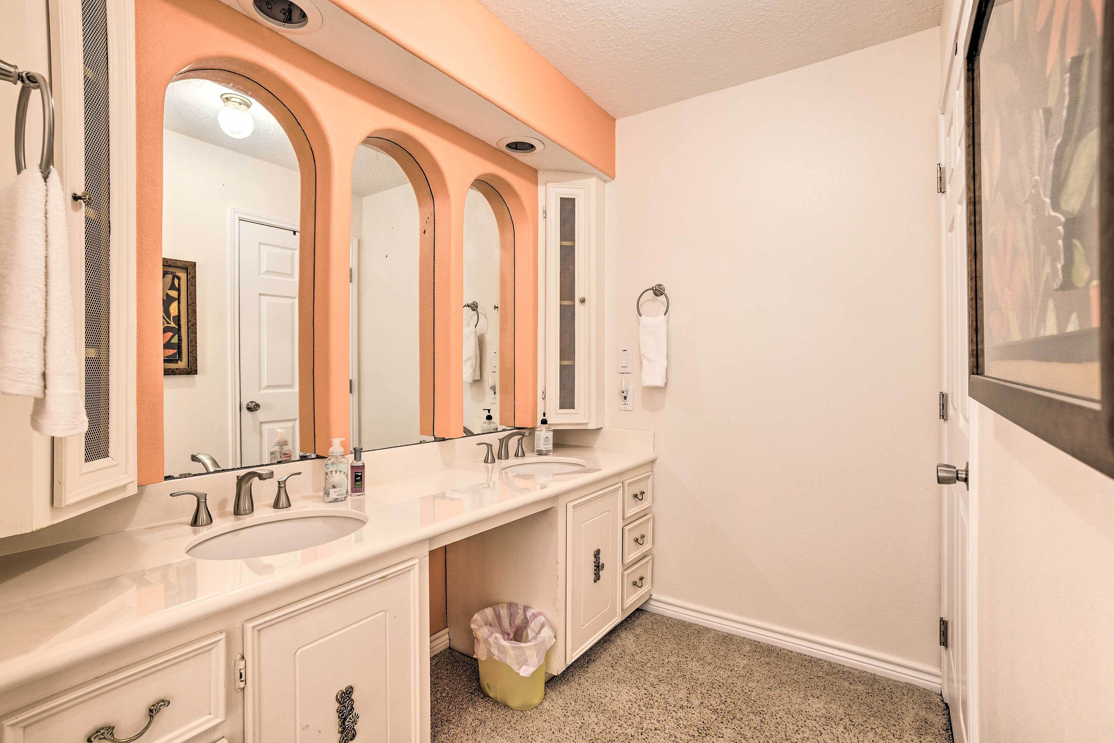 Une salle de bain avec deux lavabos, un grand miroir et une poubelle.