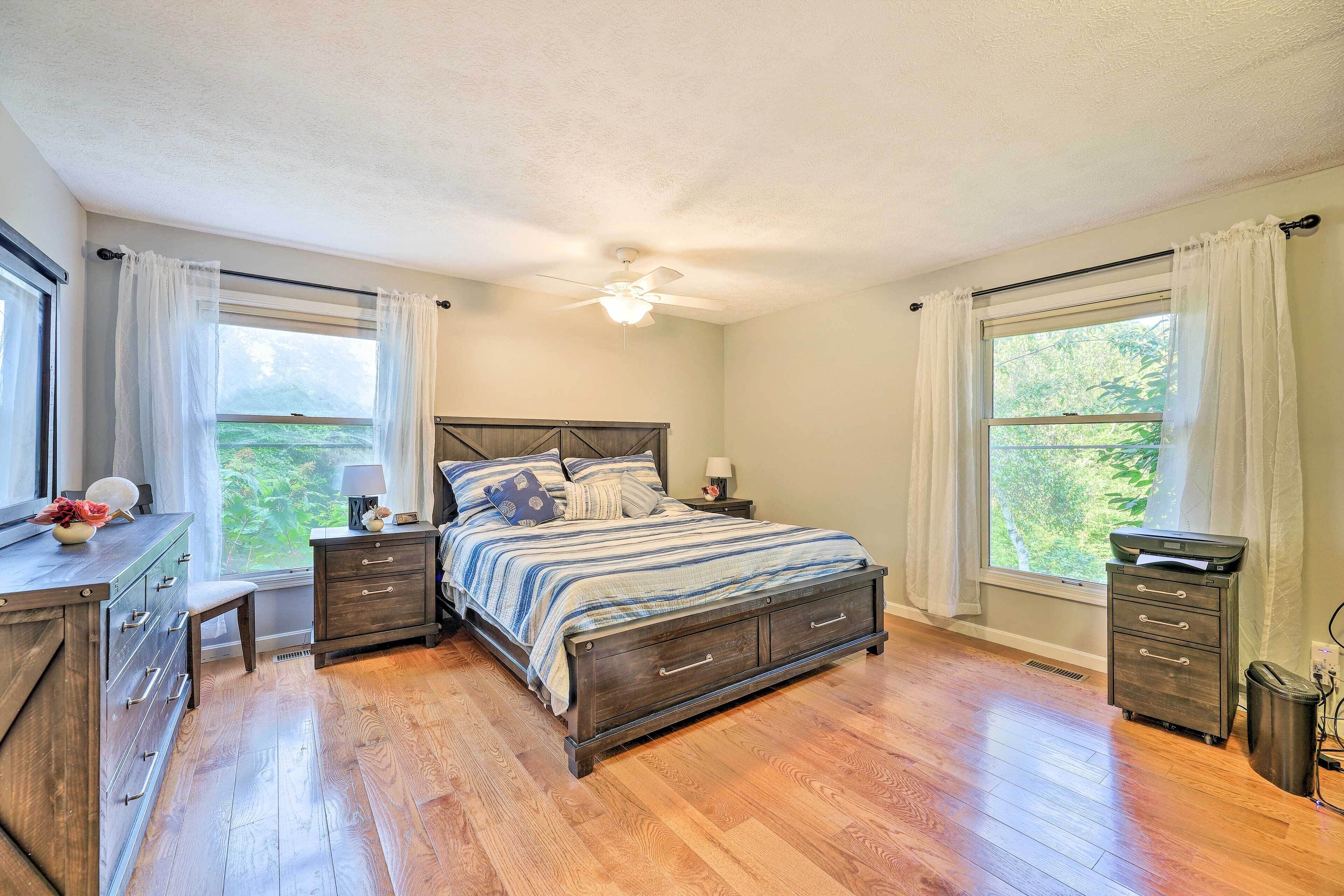 A bedroom with a bed, nightstands, a dresser, and a window with curtains.