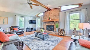 A spacious living room with a fireplace, leather sofas, a coffee table, and a television. - Family-friendly Brookville Home w/ Hot Tub! (Brookville)