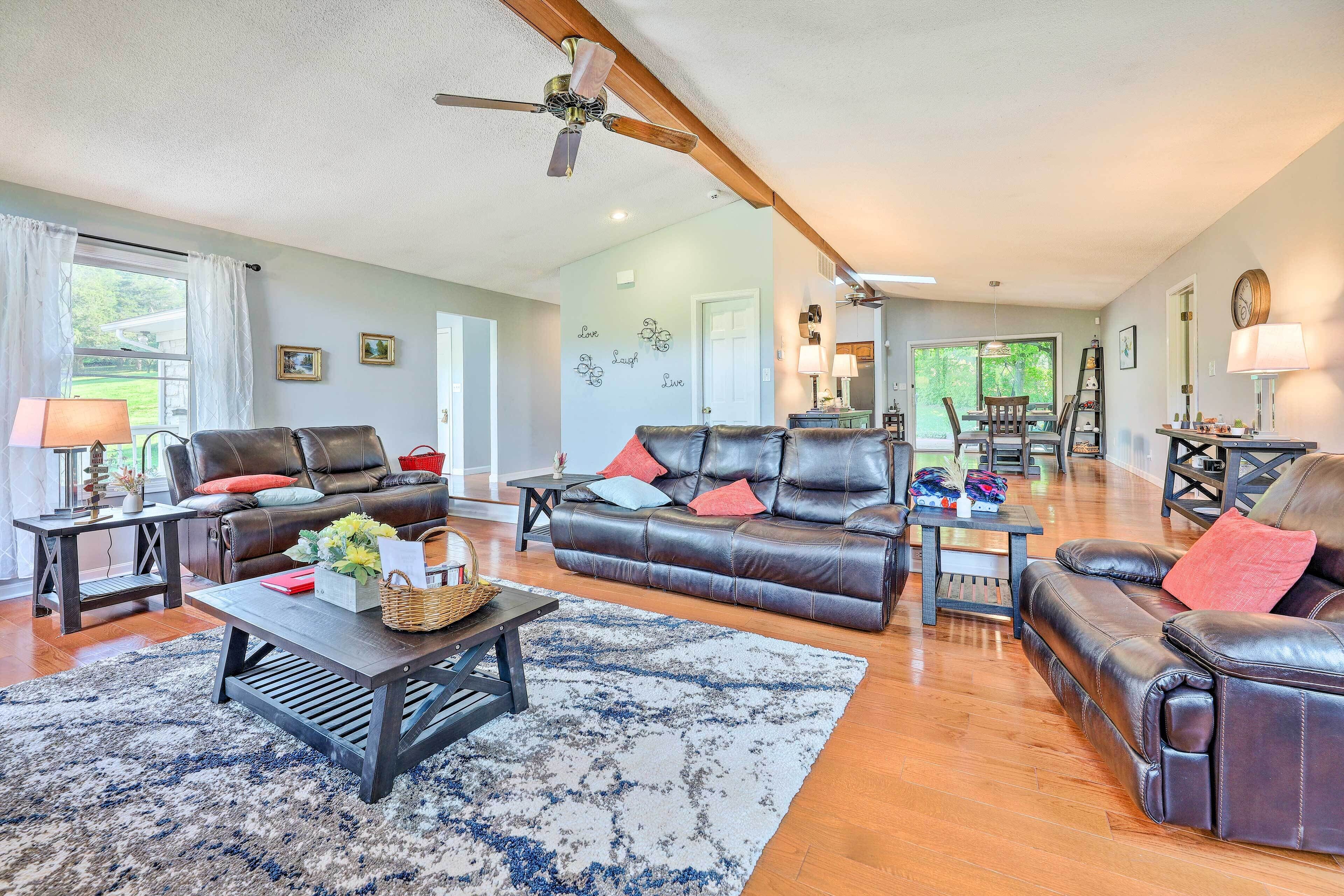 A spacious living room with leather sofas, a coffee table, and a dining area in the background.