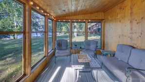 Un interior de madera con ventanas amplias, un sofá, dos sillones y una mesa con una cesta.