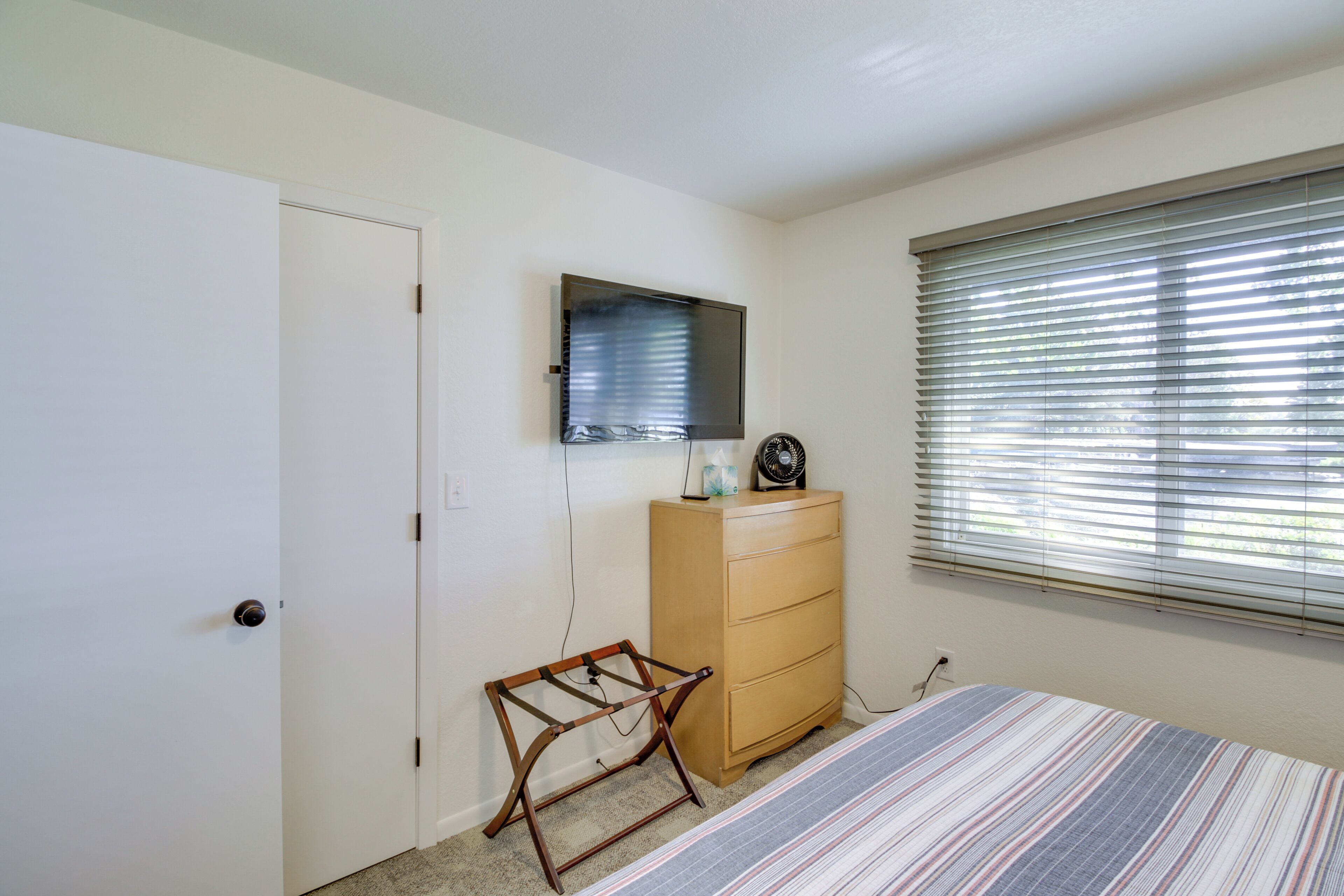 Un dormitorio con cama, cómoda, espejo y ventana con persianas.