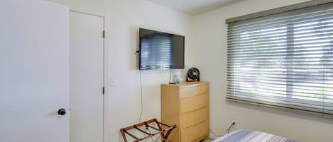 Un dormitorio con cama, cómoda, espejo y ventana con persianas.