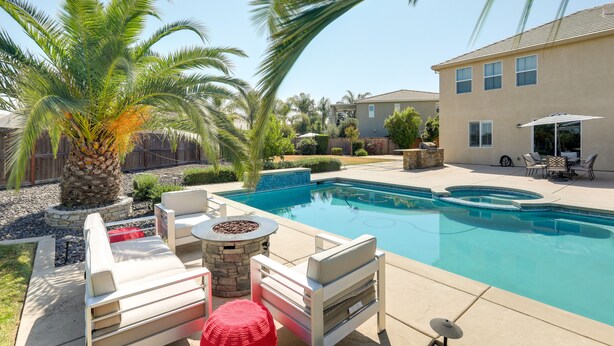 Ein Garten mit Swimmingpool, Gartenmöbeln und einer Palme.
