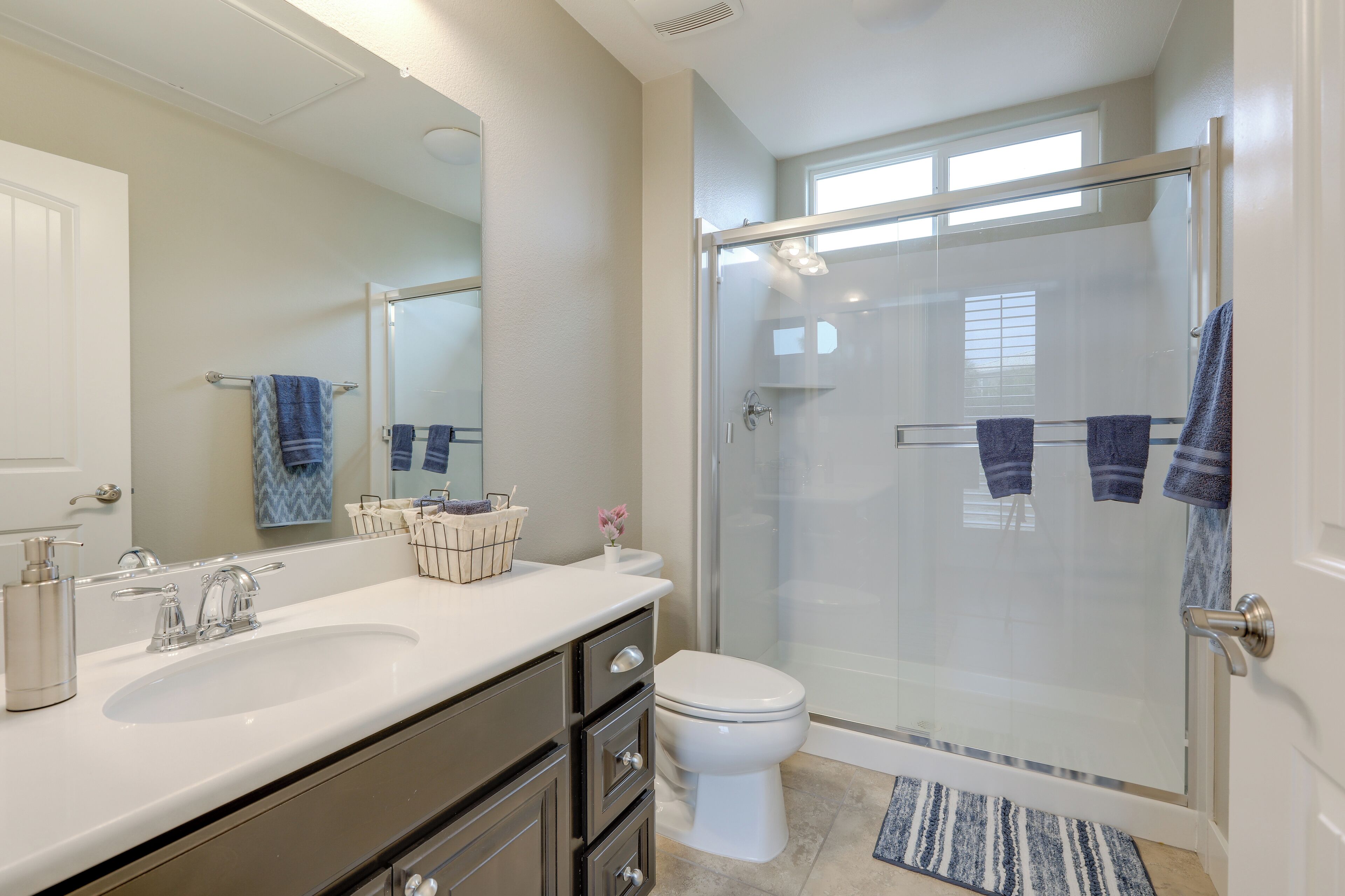 A bathroom with a glass-enclosed shower, a white sink, and a toilet.