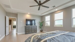 Ein Schlafzimmer mit einem großen Bett, einem Deckenventilator, einem Fernseher auf einer Kommode und einem Blumentopf.