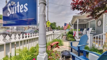Señal para el hotel 'The Suites', con mesas al aire libre, sillas azules, una valla de piquetes blancos y una bandera estadounidense.