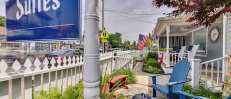 A sign for "The Suites" hotel, outdoor seating with blue chairs, a white picket fence, and an American flag.