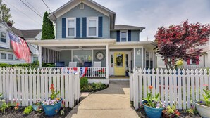 A two-story house with a porch, a front yard with potted plants, and a white picket fence. - Historic Bemus Point Studio w/ Porch: Walk to Lake (Bemus Point)