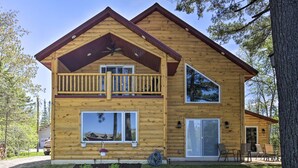A two-story log cabin with a balcony, large windows, and a sliding glass door. - Lakefront Retreat w/ Patio, Grill + Boat Dock! (Eagle River)