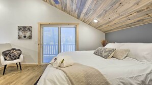 A bedroom with a sloped ceiling, a large bed, a chair, a window, and a wall-mounted picture. - Lakefront Retreat w/ Patio, Grill + Boat Dock! (Eagle River)