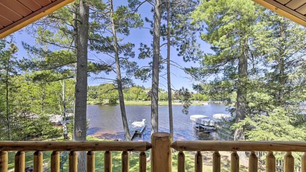 A wooden deck overlooking a lake with boats and a dock. - Lakefront Retreat w/ Patio, Grill + Boat Dock! (Eagle River)