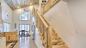 A spacious kitchen with wooden cabinets, a dining area with a table and chairs, and a wooden staircase with a ceiling fan. - Lakefront Retreat w/ Patio, Grill + Boat Dock! (Eagle River)
