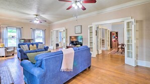 A spacious living room with a blue sofa, a ceiling fan, and a television.