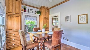 A dining area with a wooden table, chairs, and a window with curtains.