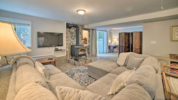 A living room with a stone fireplace, a television, and a large sofa. - Lovely Snohomish Studio Near Boating & Hiking (Snohomish)