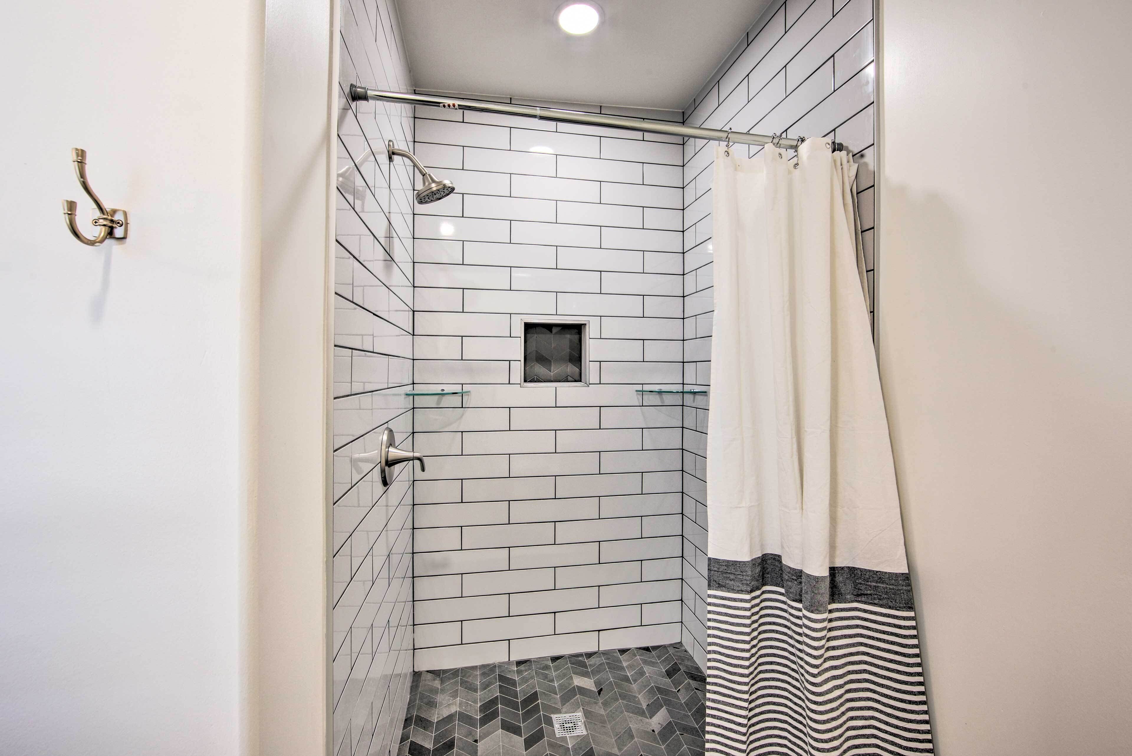 A small, tiled shower with a glass door, a showerhead, and a towel rack.