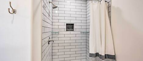 A small, tiled shower with a glass door, a showerhead, and a towel rack.