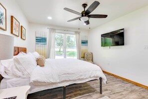 Una camera da letto con un letto, ventilatore a soffitto, televisione e opere d'arte alle pareti.