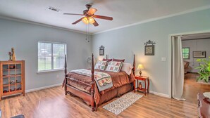 A bedroom with a four-poster bed, a ceiling fan, a window with blinds, a wooden cabinet, and a door leading to another room. - Heavenly Heber Springs Hideaway: Fish & Hike! (Heber Springs)
