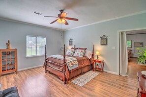 A bedroom with a four-poster bed, a ceiling fan, a window with blinds, a wooden cabinet, and a door leading to another room. - Heavenly Heber Springs Hideaway: Fish & Hike! (Heber Springs)