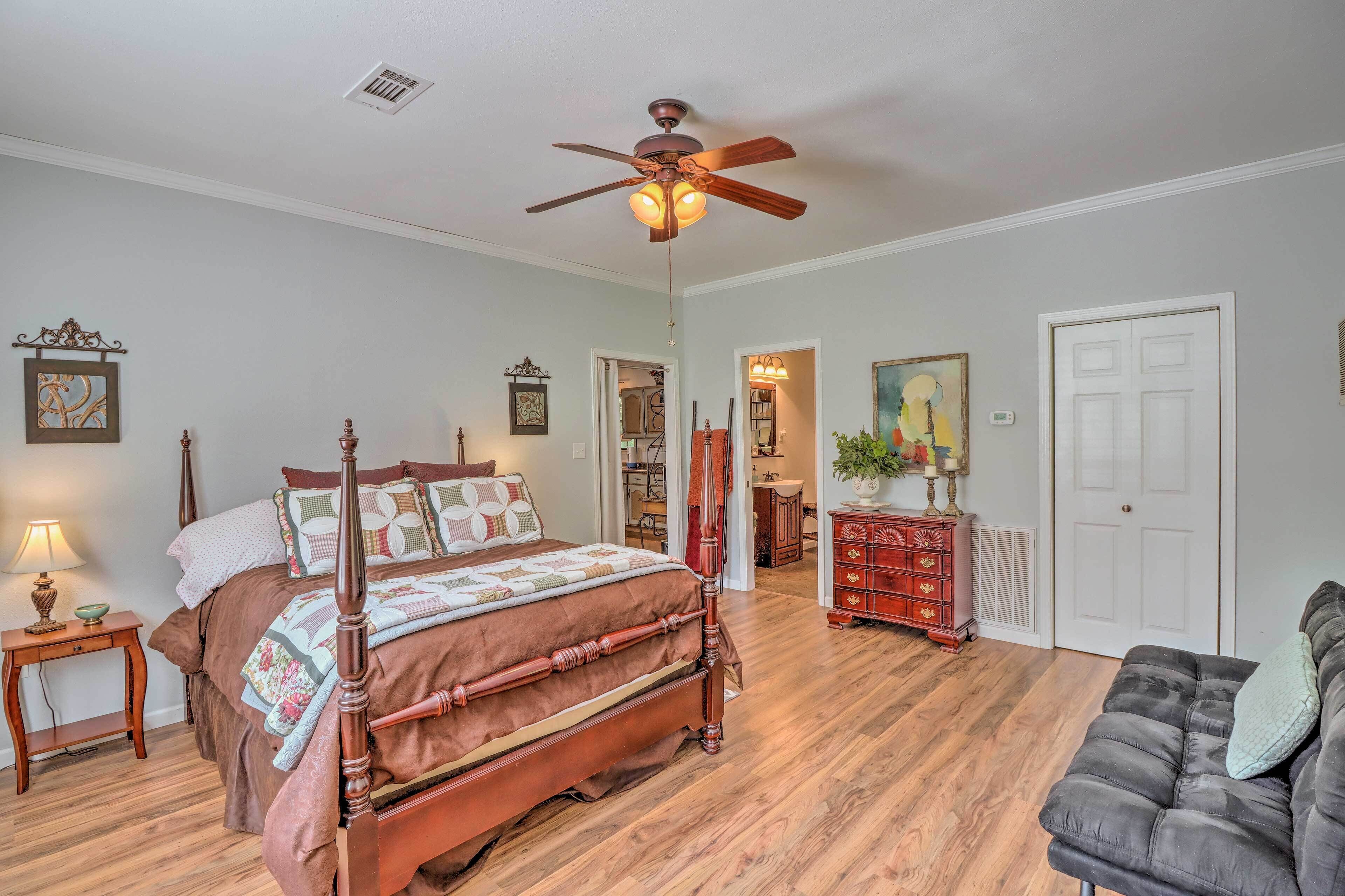A bedroom with a four-poster bed, a ceiling fan, a dresser, and a sofa.