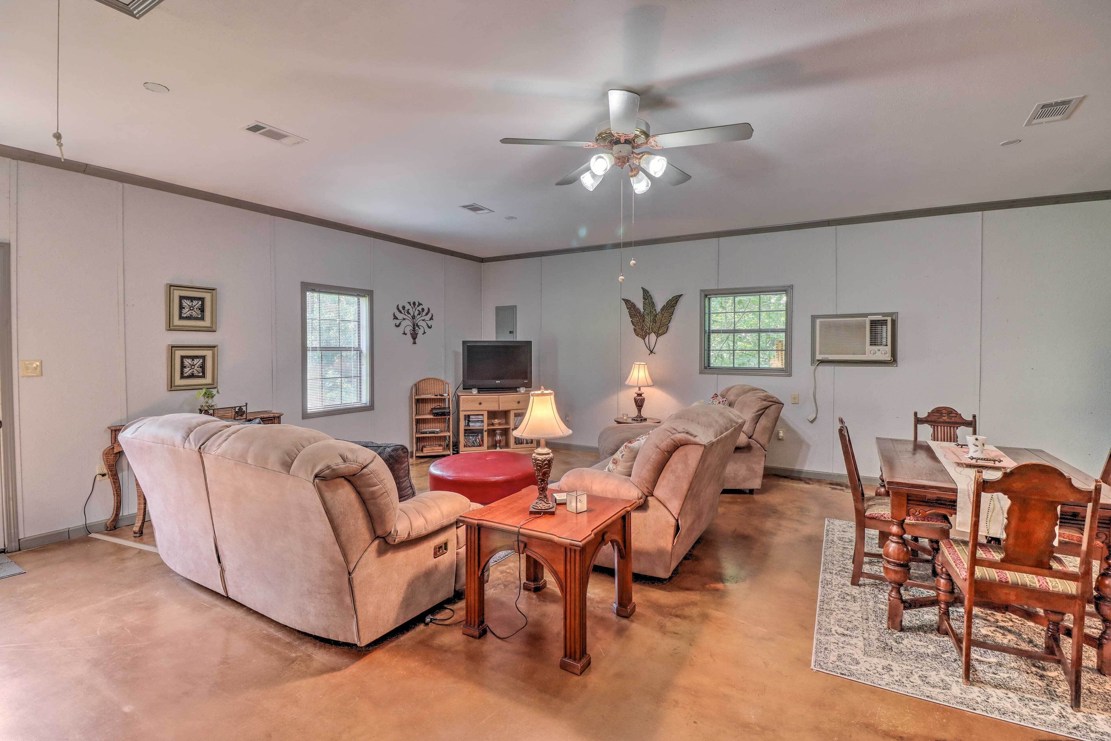 A spacious living room with a ceiling fan, a wooden coffee table, and a dining area with a table and chairs.
