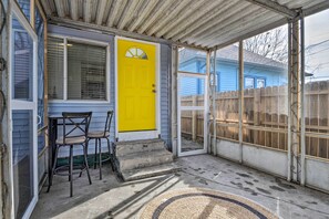 A covered porch with a yellow door, two chairs, and a concrete staircase leading to a wooden deck. - Indianapolis Home ~ 1 Mi to Fountain Square (Indianapolis)