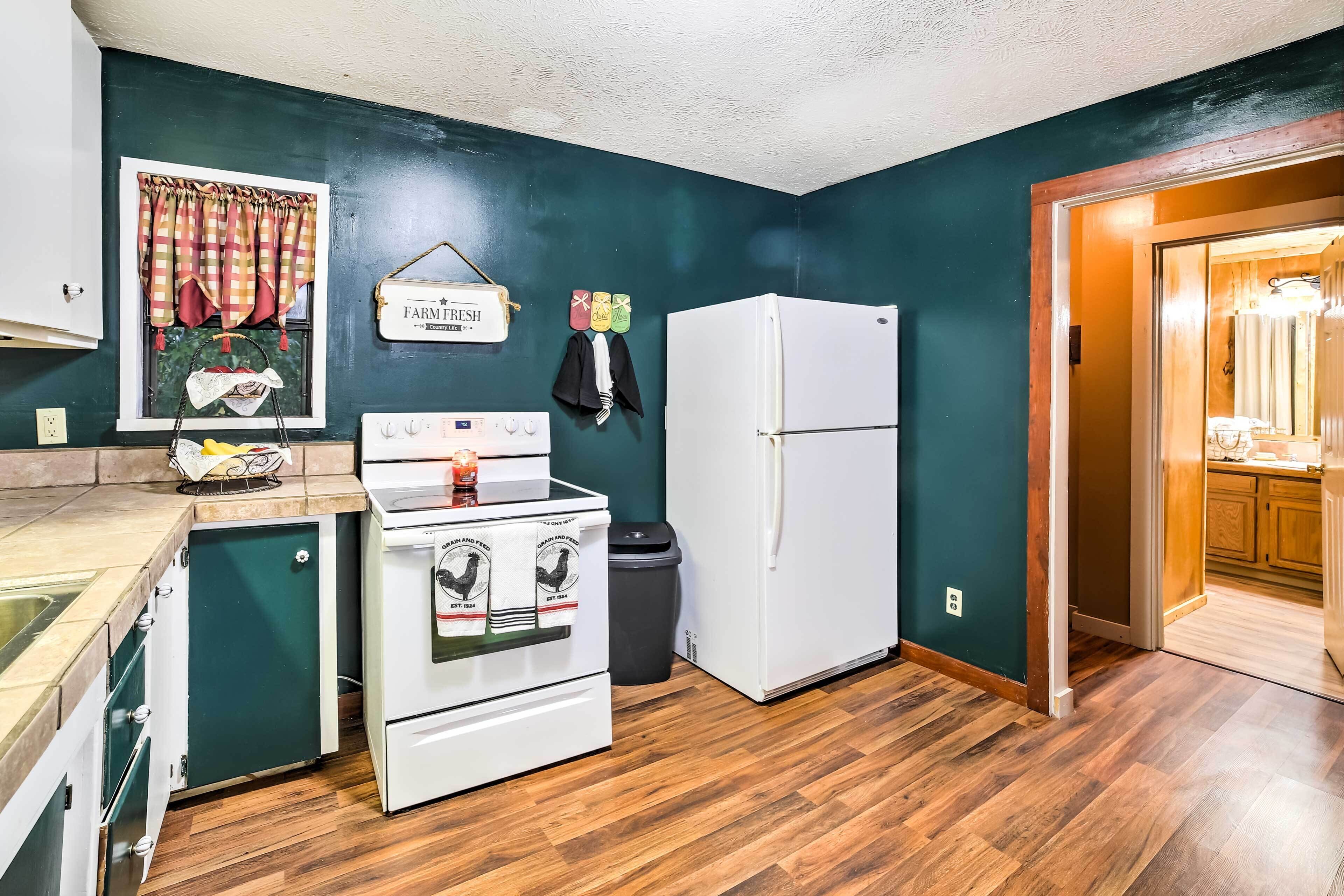Une cuisine compacte équipée d’une cuisinière, d’un four et d’un réfrigérateur, avec un plancher en bois et un mur de couleur turquoise.