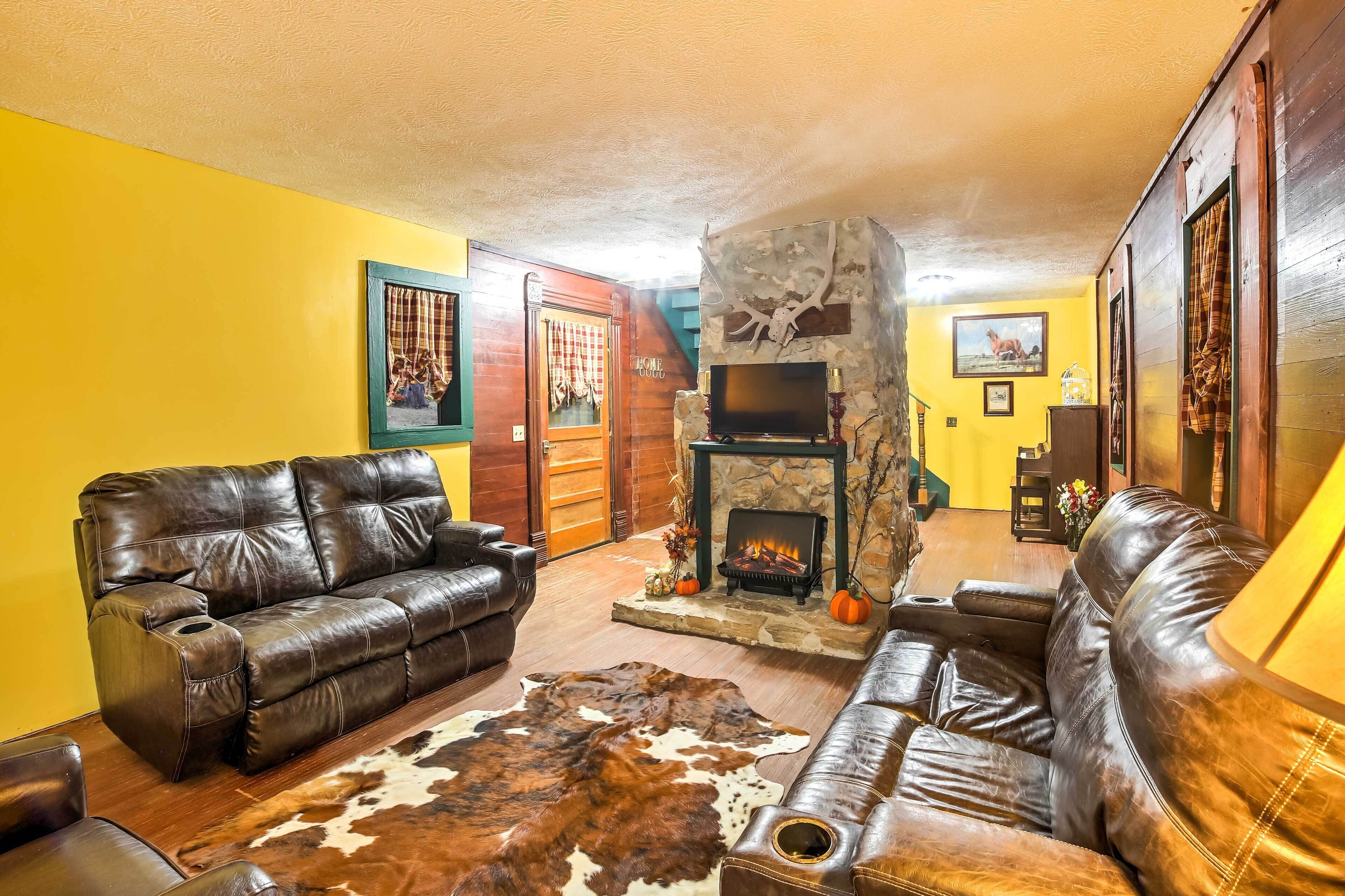 A living room with a stone fireplace, leather sofas, and a cowhide rug.