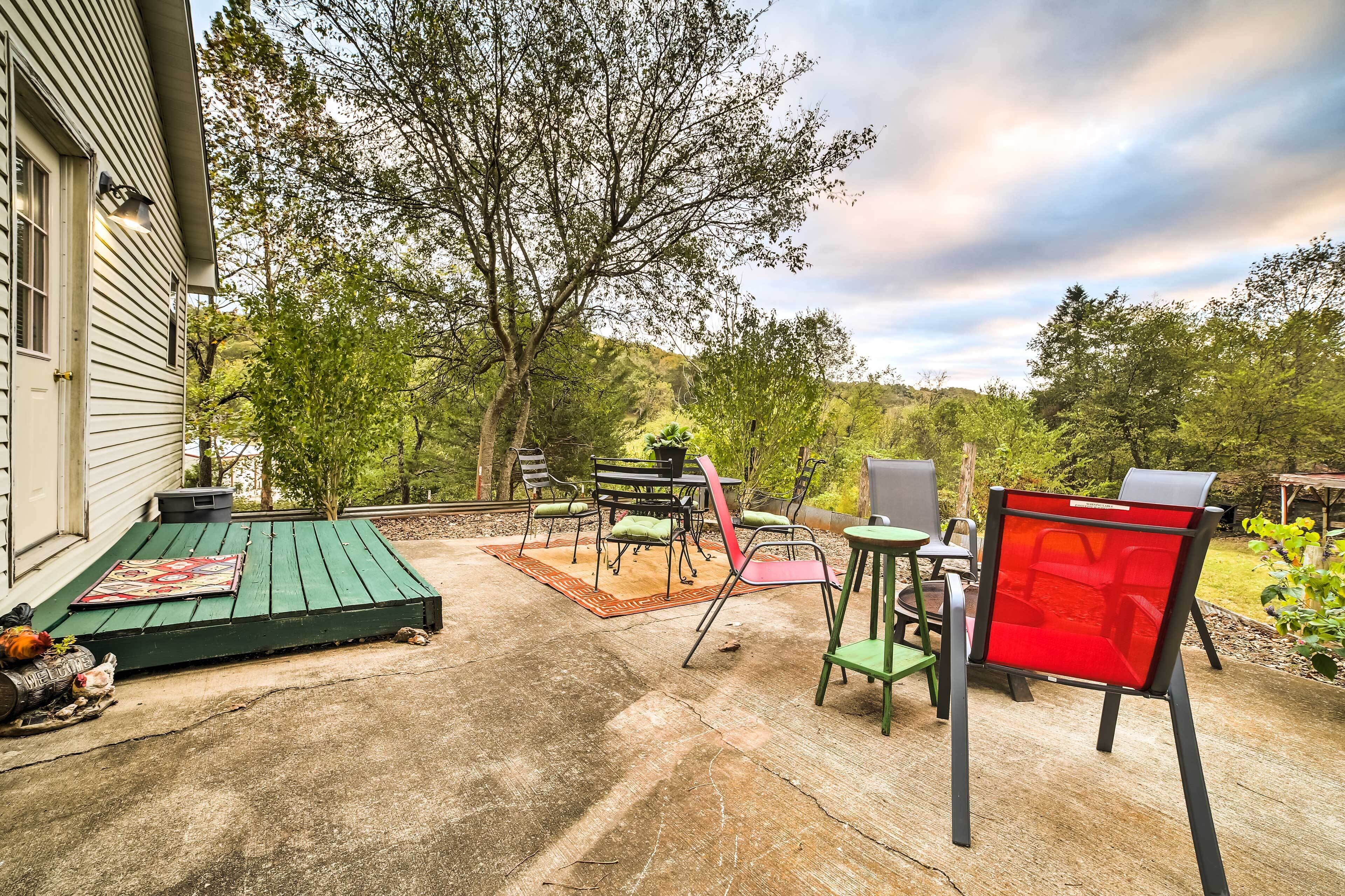 A patio with outdoor furniture, a green deck, and a view of trees and hills.
