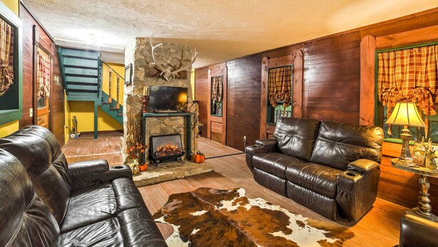 A cozy living room with a fireplace, leather sofas, and a stone wall. - Historic Bruno 'hampton Creek Hideaway' on 2 Acres (Everton)
