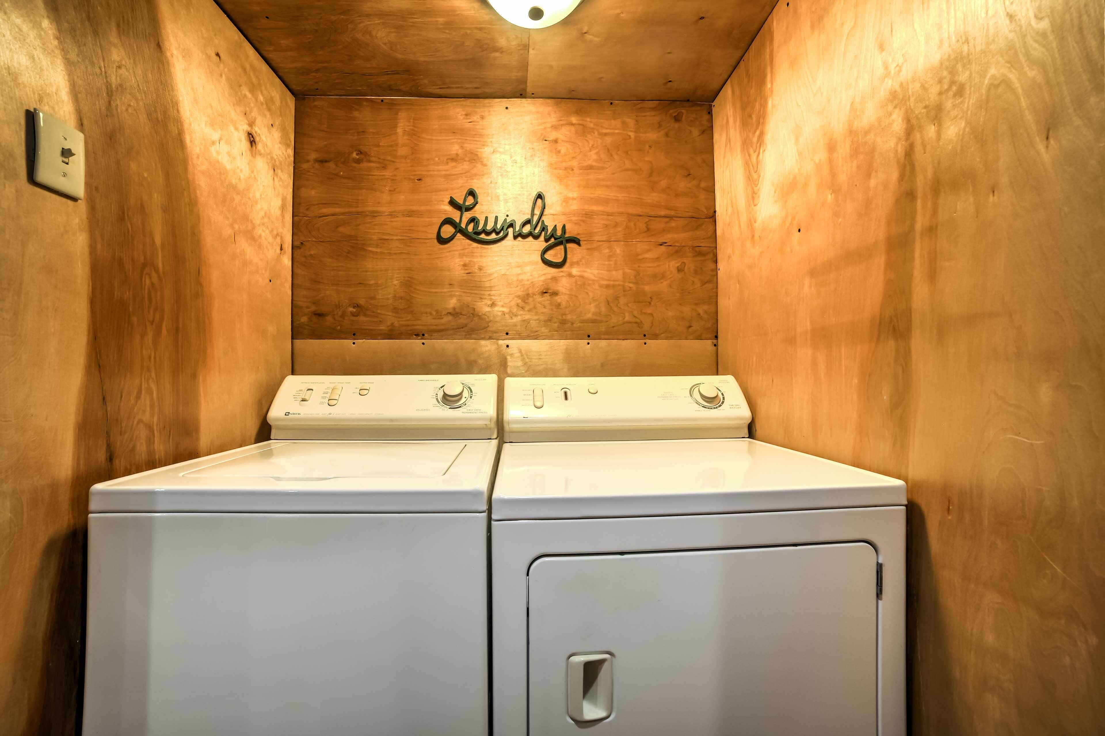 A laundry room with two white washers and dryers, wooden walls, and a 'Laundry' sign on the back wall.