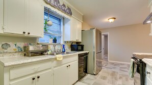 A kitchen with white cabinets, a stainless steel refrigerator, a microwave, and a dishwasher.