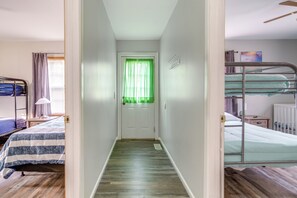 A narrow hallway with a wooden floor leading to a door with green curtains.