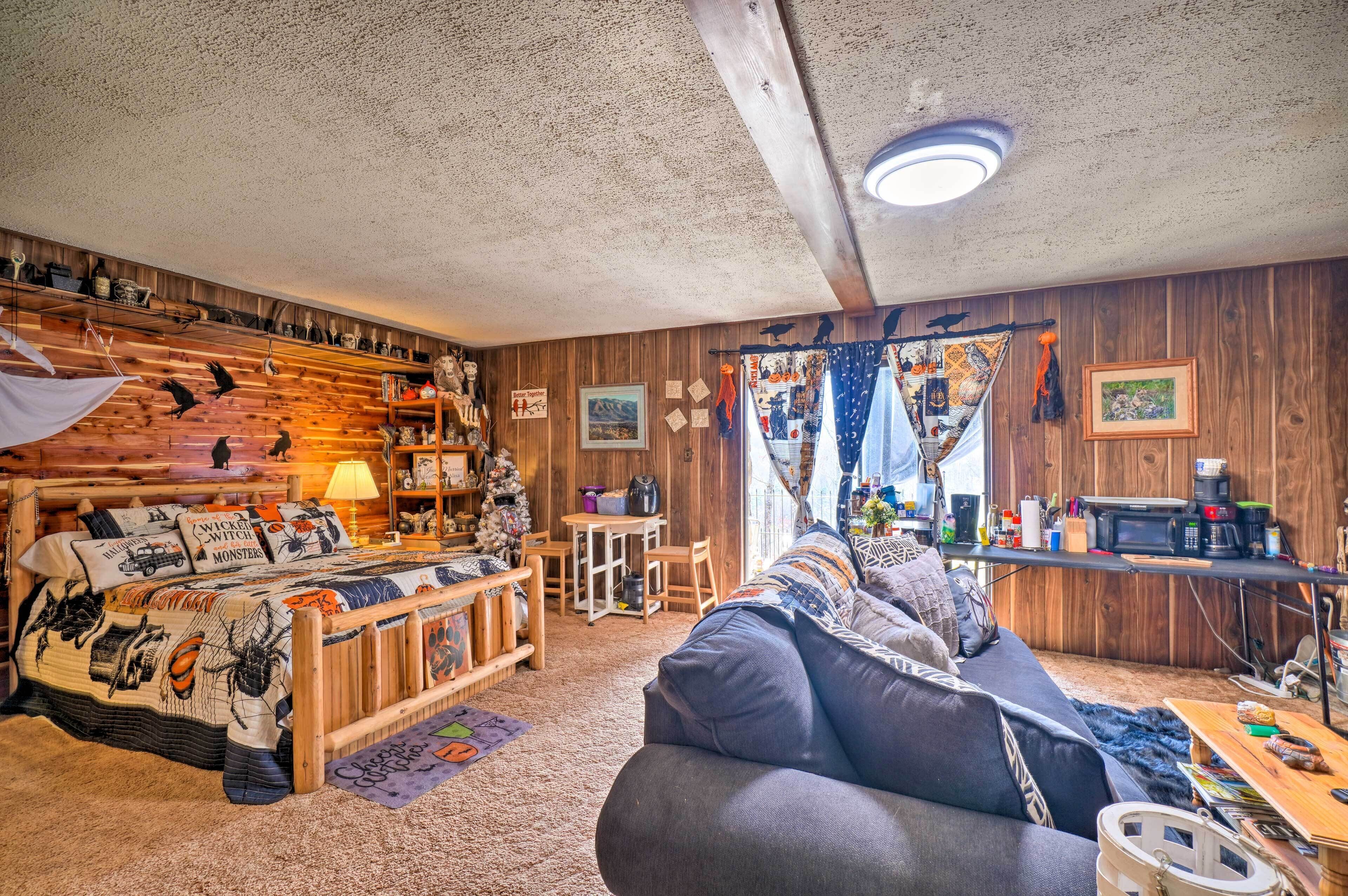 L’intérieur chaleureux d’un chalet avec un lit en bois, un canapé, un coin repas et un comptoir de cuisine.