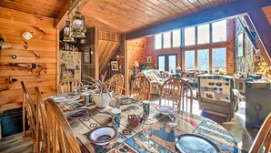 Interior acogedor de una cabaña con una mesa de comedor de madera dispuesta para cuatro personas, rodeada de sillas de madera.