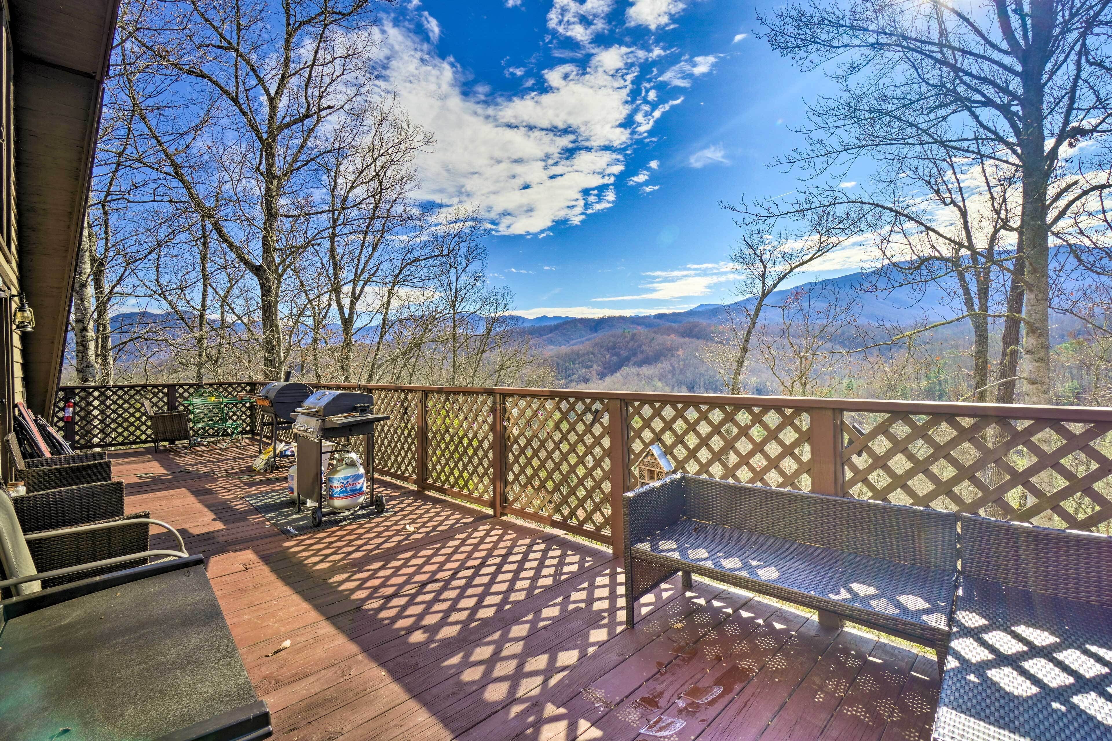 A wooden deck with a grill, a bench, and a view of mountains.