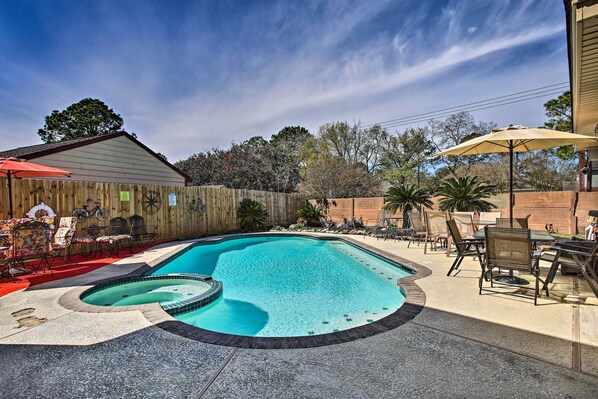 A backyard with a swimming pool, patio furniture, and a wooden fence.