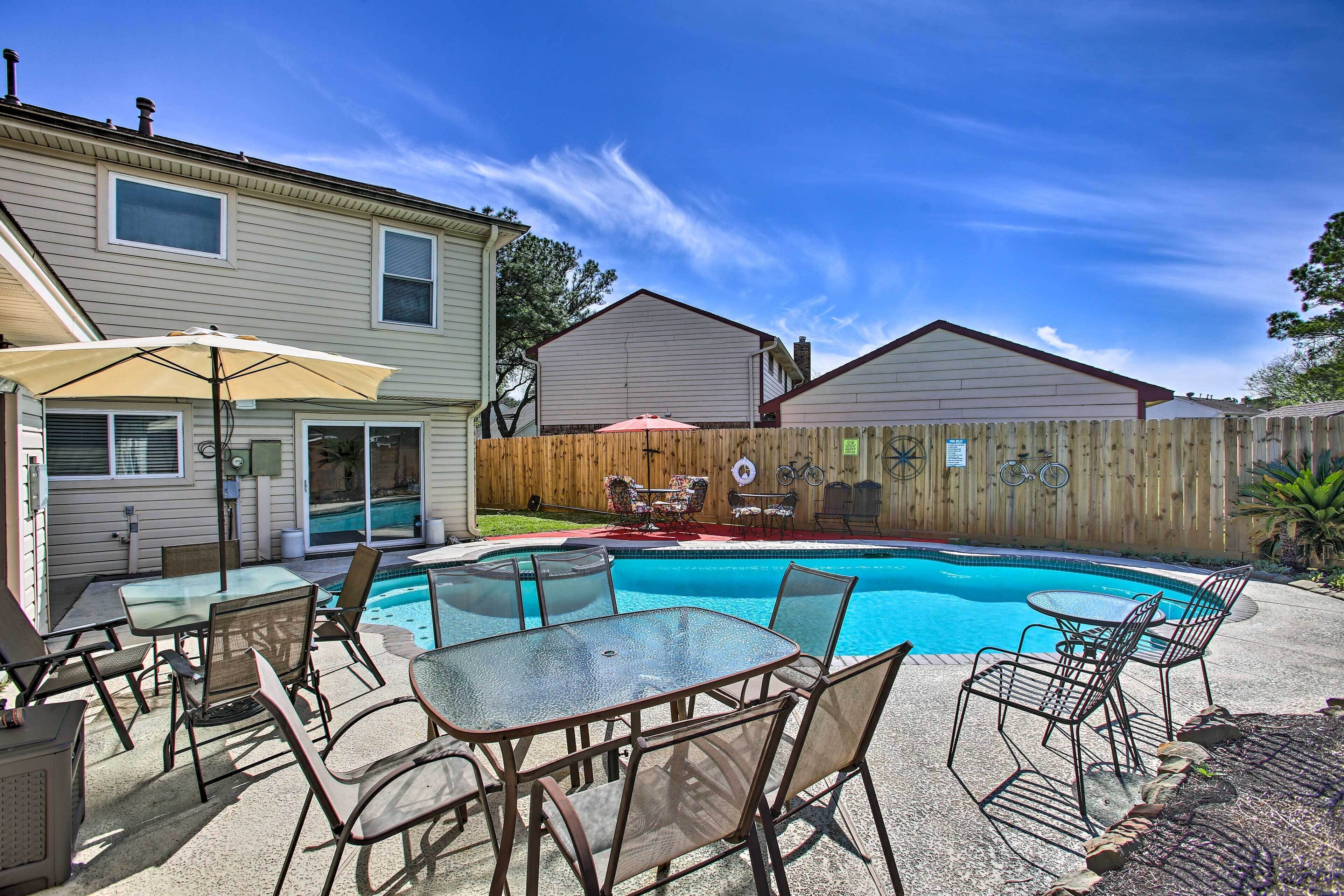 A backyard with a swimming pool, patio furniture, and a wooden fence.