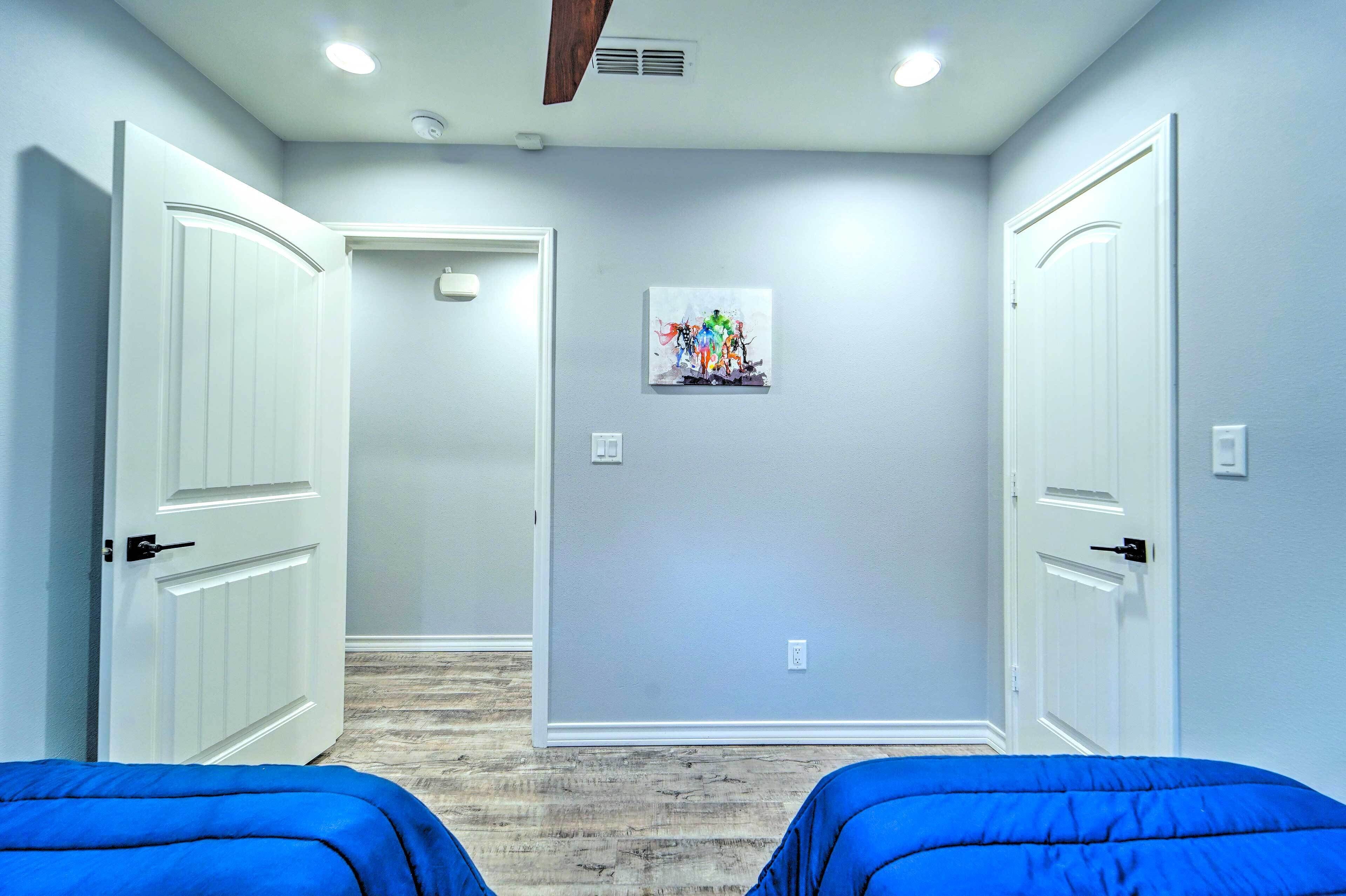 A room with two beds, a ceiling fan, and a wall-mounted artwork.