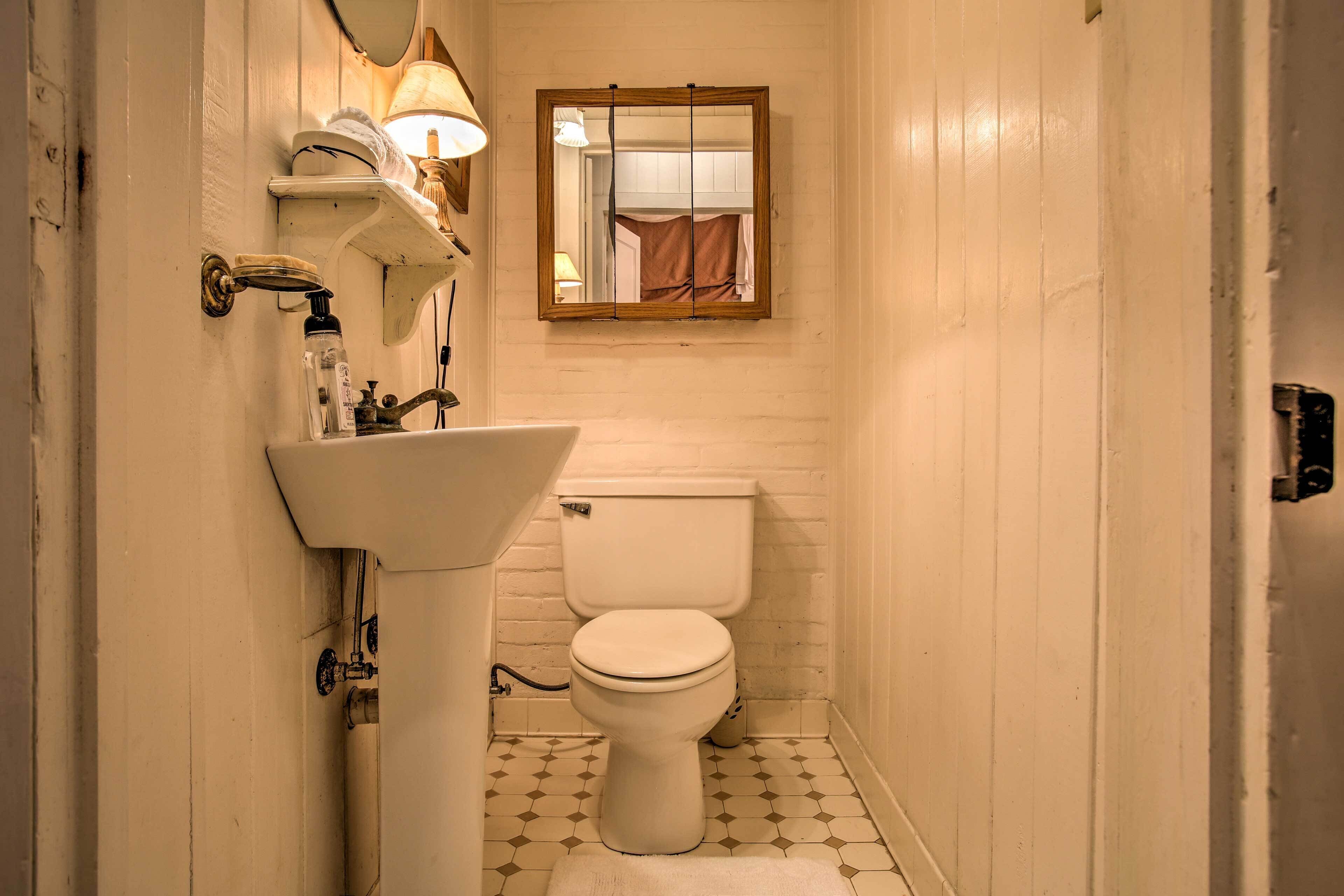 Une petite salle de bain avec des toilettes blanches, un lavabo et un miroir au-dessus.