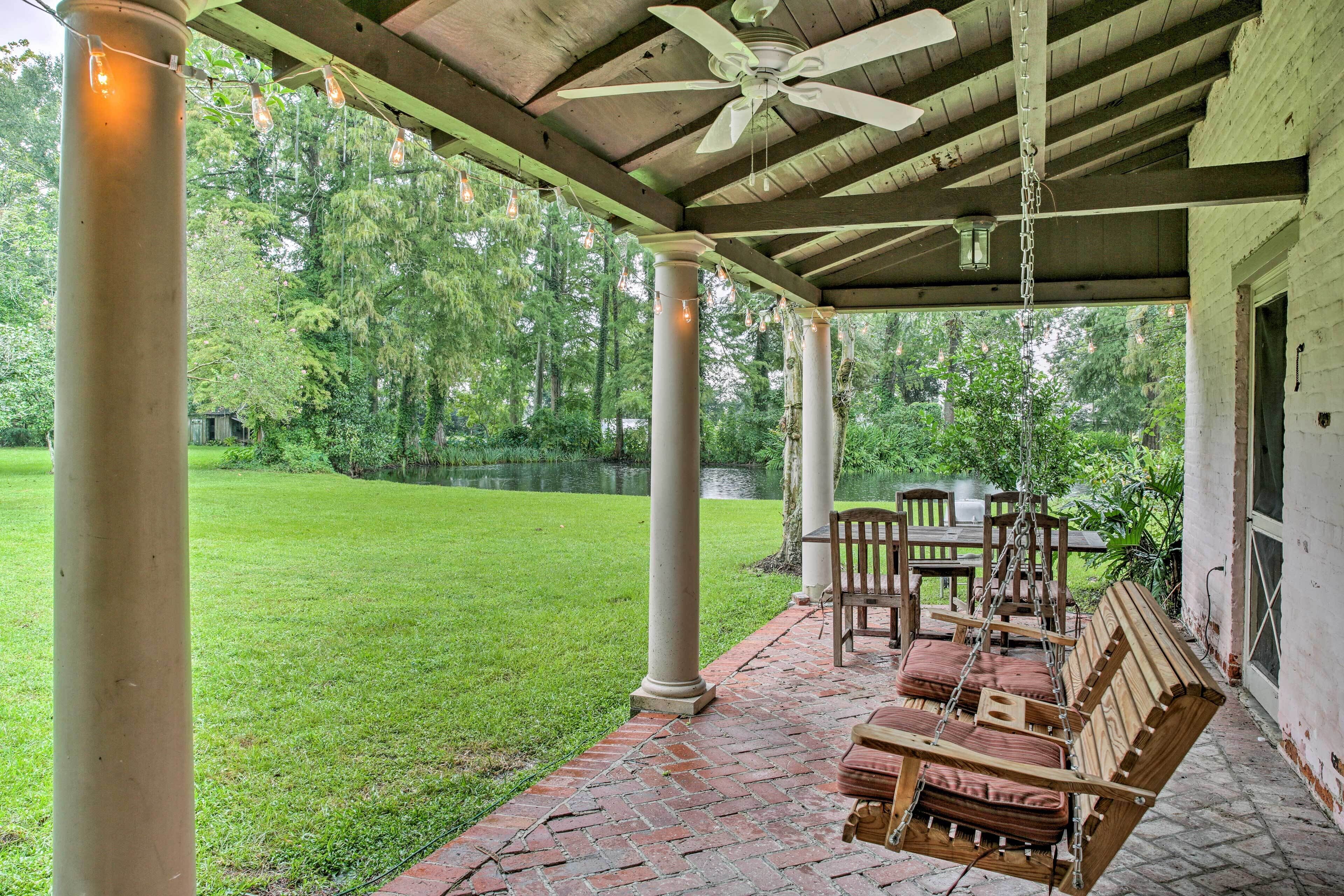 A covered patio with a swing chair, a table, and chairs.