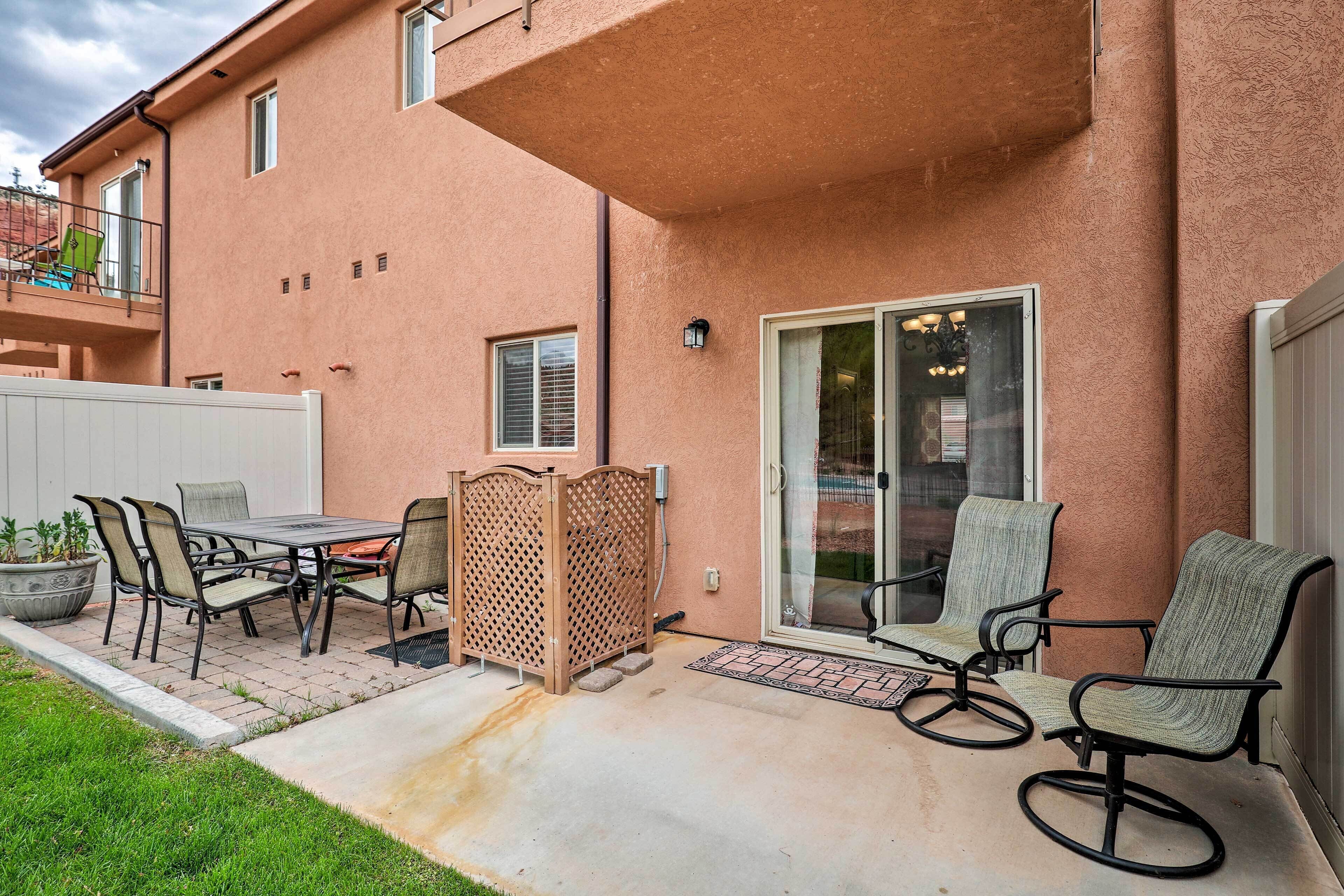 A patio with a table and chairs, a sliding glass door, and a small garden area.