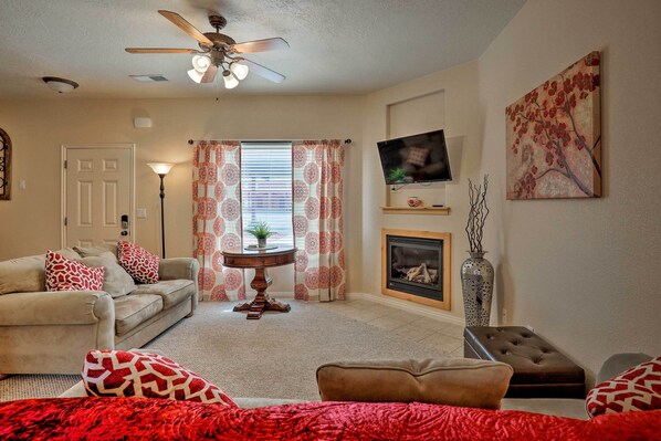 A living room with a sofa, ottoman, and a fireplace. - Kanab Condo w/ Pool & Patio, 30 Mi to Zion NP (Kanab)