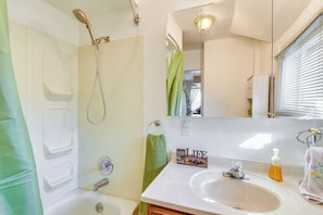 Un baño con ducha, lavamanos y espejo.