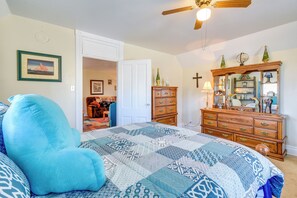 A bedroom with a large bed, a wooden dresser, a mirror, and a ceiling fan. - Lake Michigan Vacation Rental: 1 Block to Marina! (Manitowoc)