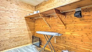 A room with wooden walls, a wooden floor, an ironing board, a shelf with items, and a hanging bag. - 'lochview Lodge' Idyllic Farmhouse in Grove! (Grove)