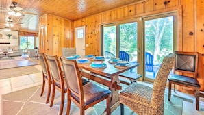 A wooden interior with a dining table set for six, surrounded by chairs, and a wicker chair in the foreground. - 'lochview Lodge' Idyllic Farmhouse in Grove! (Grove)