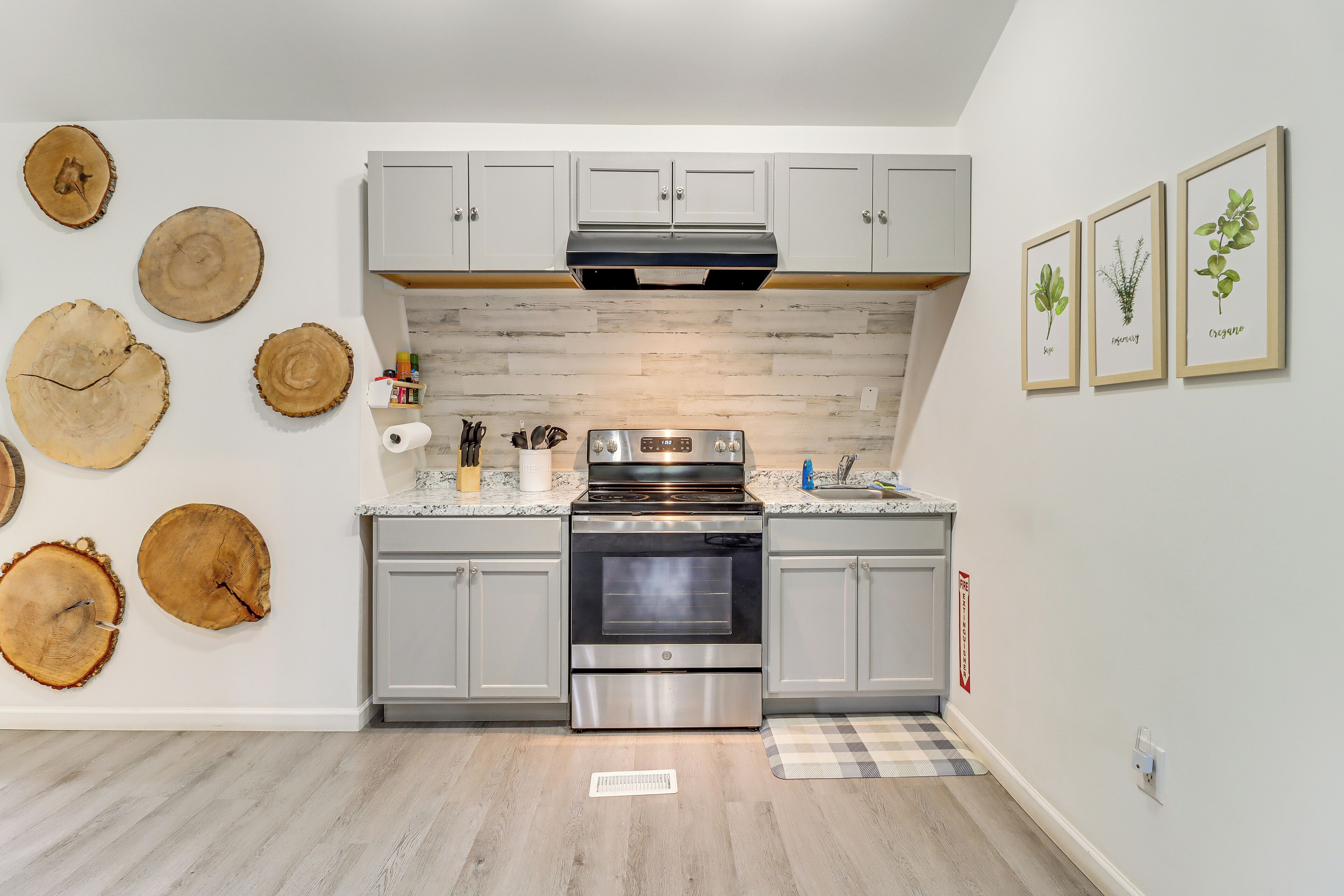 A modern kitchen with grey cabinets, a stainless steel oven, and a central island.